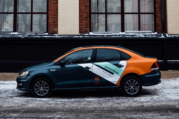 Автомобиль каршеринга на городской улице как символ снижения поездок и операционных вызовов сервиса