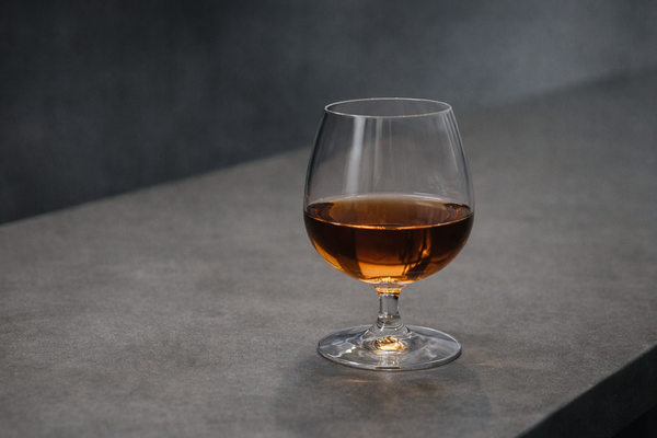 Бокал коньяка на нейтральной поверхности как символ категории крепкого алкоголя и импортного сегмента рынка