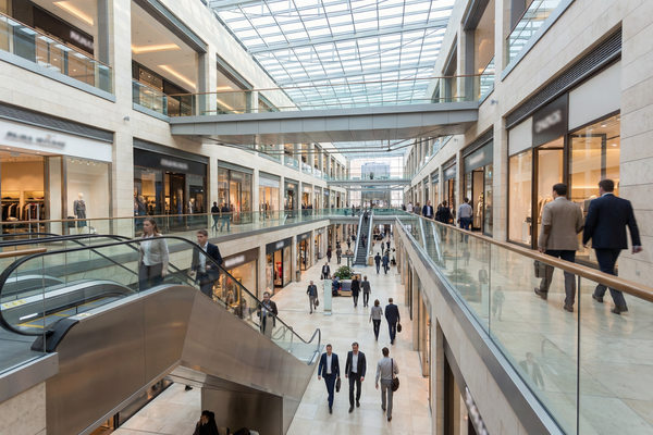 Атриум крупного торгового центра в Москве с витринами международных брендов и потоком посетителей