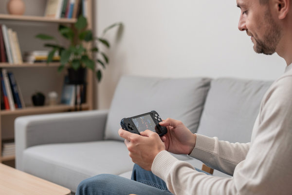 Мужчина играет на портативной игровой консоли в домашней обстановке