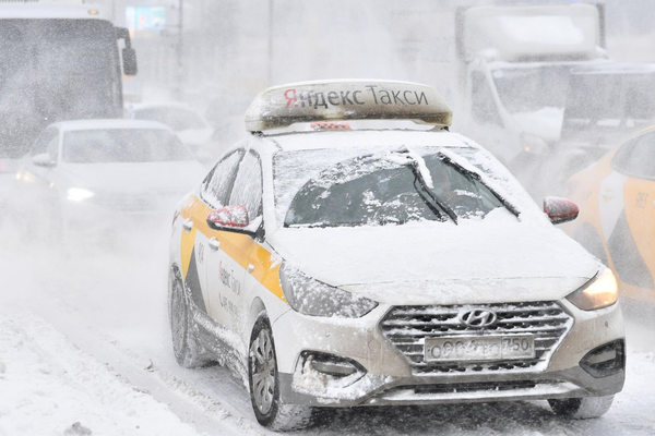 Автомобиль «Яндекс Такси» в снегопад на городской улице — иллюстрация к статье о погодном тарифе и росте цен на такси в условиях аномальной погоды
