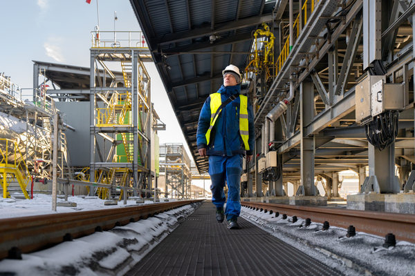 Сотрудник на промышленном терминале в Усть-Луге на фоне инфраструктуры перевалки минеральных удобрений и железнодорожных путей