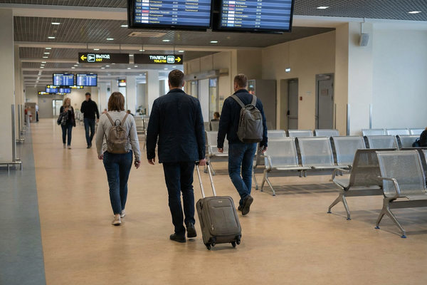 пассажиры с ручной кладью в аэропорту, снижение спроса на путешествия и изменение пассажиропотока