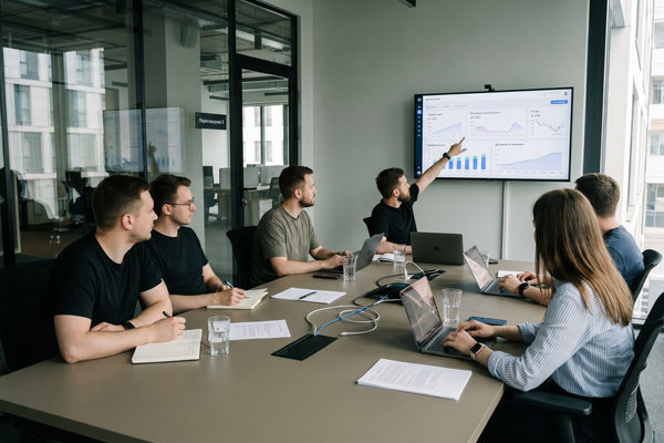 Команда цифровой компании обсуждает экосистемные подписки, платящих пользователей и динамику роста на офисном дашборде