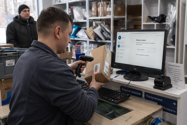 Сотрудник пункта выдачи заказов сканирует посылку в ПВЗ маркетплейса — контроль за маркетплейсами и цены в онлайн-торговле