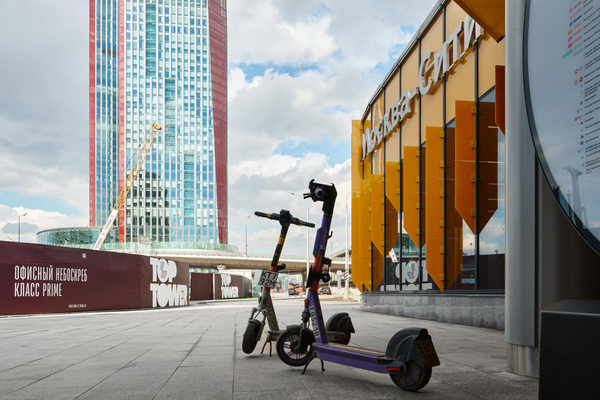 электросамокаты у входа в Москва-Сити на фоне офисных башен и нового транспортного узла