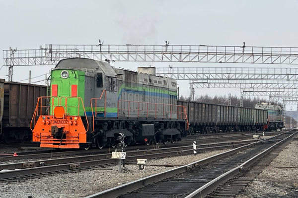 Грузовой поезд с полувагонами на железнодорожных путях как пример маршрутных перевозок