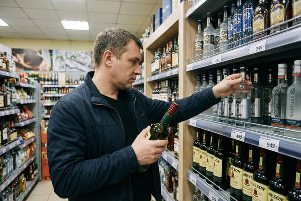 покупатель выбирает водку в магазине на фоне роста цен на крепкий алкоголь в России