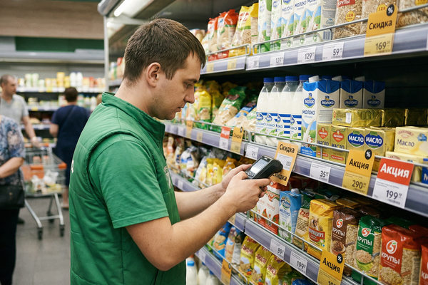 сотрудник супермаркета меняет ценники на полке с товарами, скидки и обычные цены в ритейле