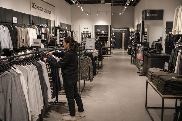 Рынок одежды в России: сотрудник fashion-магазина в почти пустом торговом зале при снижении спроса и падении продаж одежды