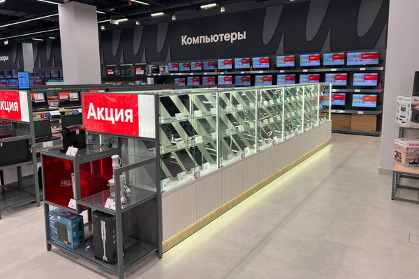 Витрина с планшетами и компьютерами в магазине электроники на фоне акции и торгового зала