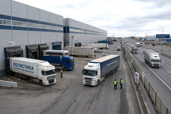 складской комплекс в Подмосковье с грузовиками у доков и выездом на автомагистраль, логистика и распределительные центры