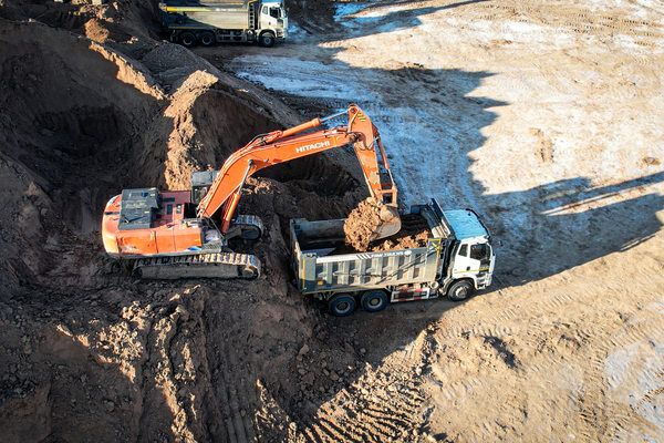 экскаватор Hitachi загружает грунт в самосвал на строительной площадке, аренда спецтехники и сервисная модель