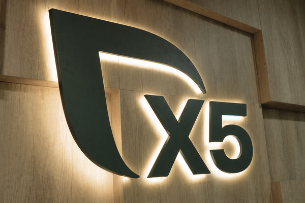 Логотип X5 на стене офиса, статья о товарных потерях, прогнозе спроса и валовой марже в ритейле