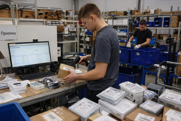 Сотрудник склада сканирует коробку с электроникой в зоне приемки зарубежных заказов
