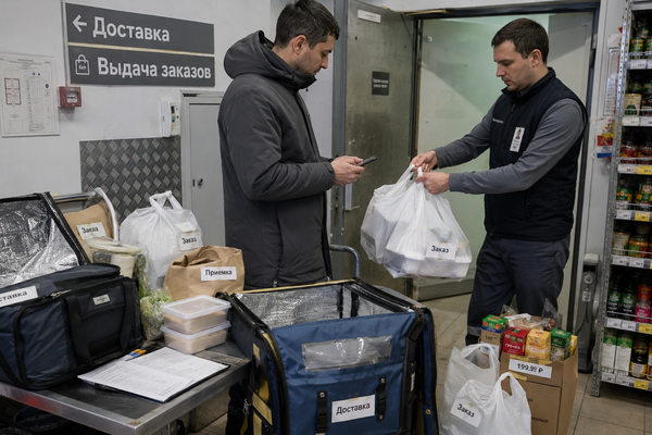 Курьер получает онлайн-заказ продуктов у сотрудника магазина в зоне доставки и выдачи заказов
