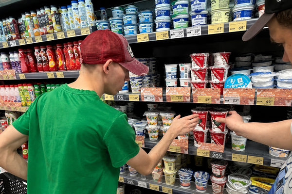 Подростки у полки с молочной продукцией в магазине ритейла во время обучения операционным навыкам