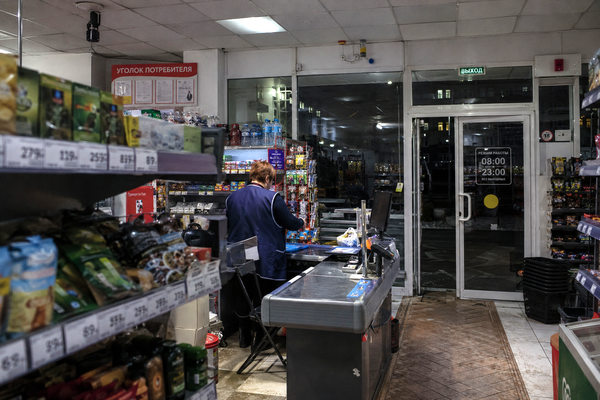 Кассир в почти пустом продуктовом магазине вечером, круглосуточные магазины и ночная торговля в ритейле