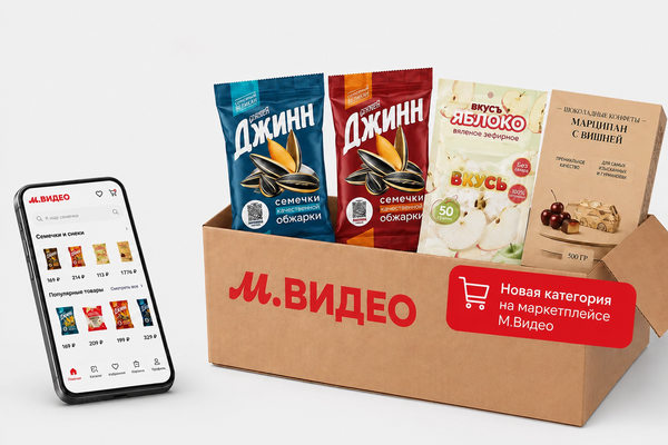 Коробка М.Видео со снеками и сладостями рядом со смартфоном с каталогом маркетплейса