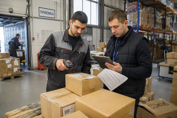Проверка партии электроники на складе при параллельном импорте: сотрудник сканирует коробку, менеджер сверяет документы