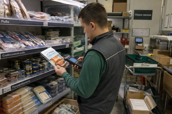 Сотрудник e-grocery сканирует рыбную продукцию у холодильной полки для контроля запасов и заказов