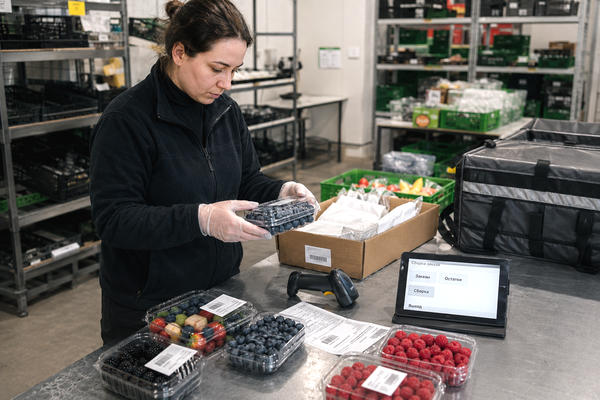 Сотрудник фреш-зоны проверяет ягоды при сборке онлайн-заказа в e-grocery