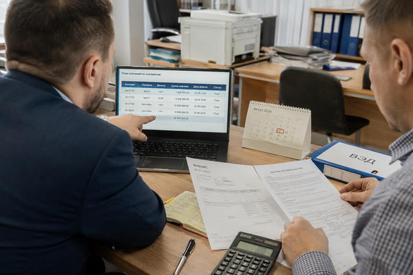 Финансовые менеджеры сверяют валютные платежи и документы ВЭД в офисе на фоне рисков для курса рубля