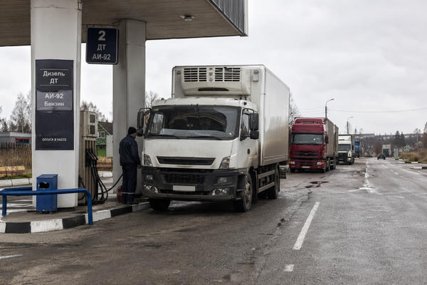 Рефрижераторный грузовик с поставкой скоропортящихся продуктов заправляется на АЗС во время топливного дефицита