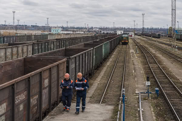 Сотрудники железнодорожной станции рядом с пустыми грузовыми вагонами на сети РЖД