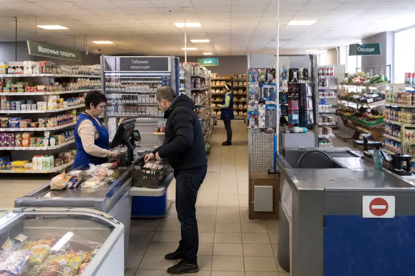 Покупатель у кассы в продуктовом магазине на фоне пустой кассовой зоны