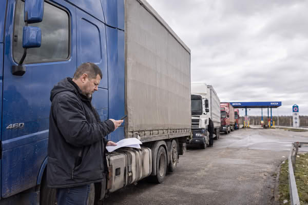 Водитель грузовика проверяет маршрут в очереди на АЗС из-за дефицита топлива