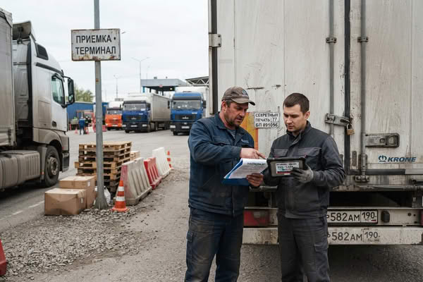 Водитель и логист сверяют документы у грузовика на терминале автодоставки из Китая
