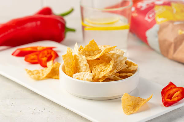 Чипсы в миске на столе — иллюстрация к статье о спросе на снеки, ассортименте и планировании запасов в ритейле