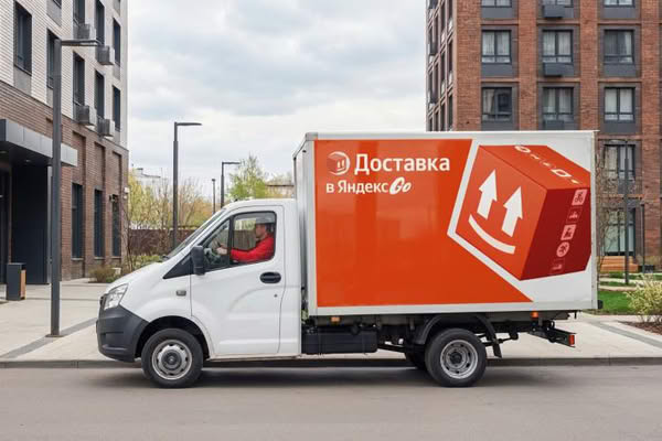 Автомобиль Яндекс Доставки для last mile на фоне жилых домов — быстрая доставка онлайн-заказов АШАН