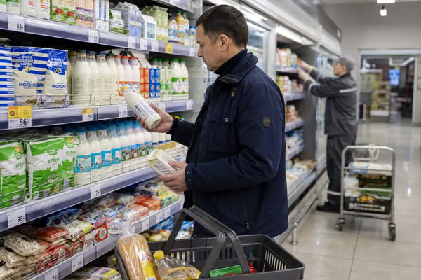Покупатель сравнивает молочные продукты и цены в продуктовом супермаркете