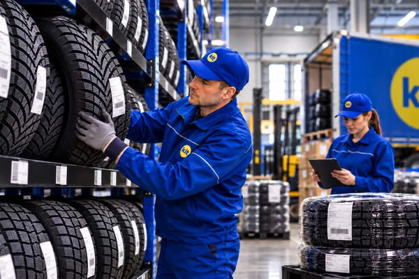 Сотрудники логистического комплекса работают с автомобильными шинами при подготовке груза к перевозке