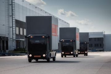 Автономные электрогрузовики Evocargo N1 в колонне на территории логистического комплекса Fplus в Подмосковье.