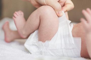 Родитель надевает подгузник на младенца — символ роста доверия к брендам BabyGo и Manu от «Детского мира»