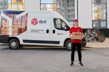 Курьер DPD с посылкой на фоне брендированного фургона компании на улице у жилого комплекса