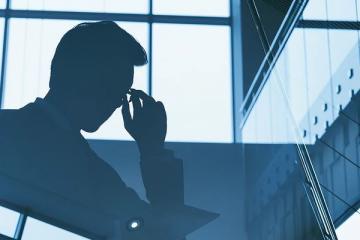 Силуэт бизнесмена на фоне офиса — символ давления регуляторов на бизнес