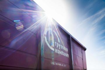 Фирменный вагон Первой грузовой компании (ПГК) на фоне яркого солнца и синего неба, символизирующий обновление ремонтной инфраструктуры