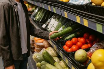Покупатель выбирает свежие овощи на полке супермаркета — регулирование цен и долгосрочные контракты в продовольственном ритейле