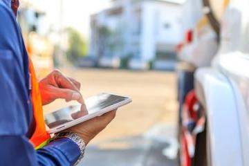 Логист использует планшет для оформления электронных перевозочных документов рядом с грузовым автомобилем