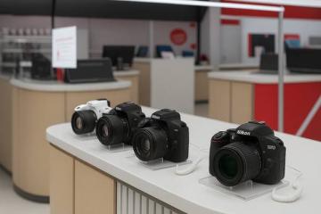 Витрина с цифровыми фотоаппаратами Nikon и Canon в магазине электроники