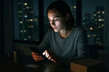 Женщина совершает онлайн-покупку ночью с помощью смартфона на фоне городских огней