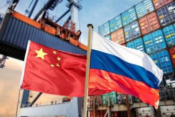 Флаги Китая и России на фоне контейнерного терминала и портового крана — символ торгово-экономического взаимодействия двух стран на фоне снижения товарооборота