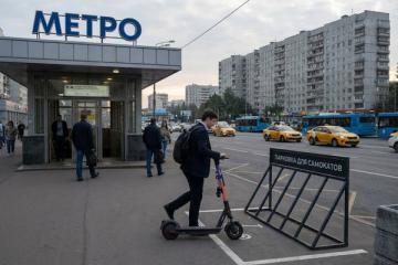 Мужчина в деловой одежде паркует электросамокат у метро в Москве — кикшеринг как часть городской транспортной системы